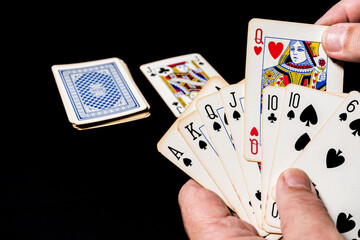 Poker card game on a table. Hand holding some cards showing his game. Select one card to discard.
