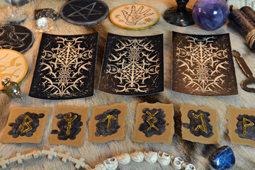 Tarot cards and runes with magic ritual objects and crystals on witch table.