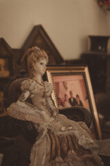 retrato de una muñeca de porcelana con fotografías viejas de fondo y desenfocadas