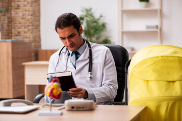 Young male doctor looking after new born in the clinic