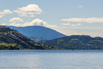 calm morning lake in British Columbia Canada blue sky with white clouds.