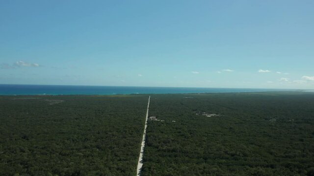 This drone shot features the stark contrast between the Mayan Jungle and a long road streaching to the Caribbean ocean in Tulum, Mexico.