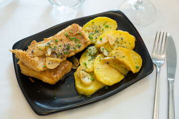 Delicious spicy breaded roasted ray wings served with potatoes. Typical Basque dish..