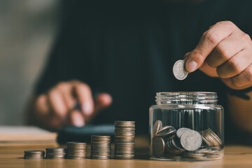 businessman holding coins putting in glass with using calculator to calculate concept saving money for finance accounting, Business, finance, investment, Financial planning.