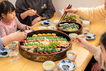 自宅で出前寿司を食べる家族