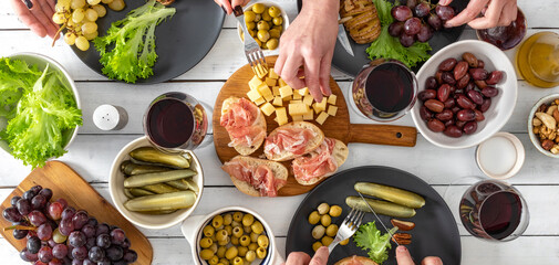 Snack dinner table concept. Bruschetta with ham, cheese, baked potatoes, olives and olives with wine top view
