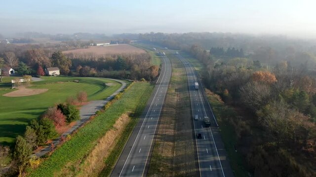 Aerial of interstate commerce, shipping on highway. Tractor trailers haul e-commerce shopping across USA.