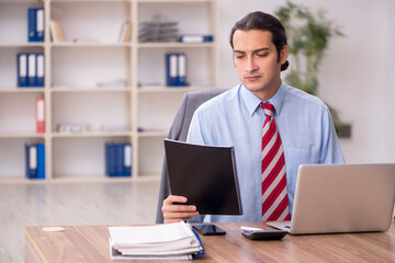 Young male employee sitting at workplace