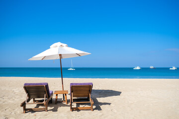 White beach umbrella on the beach against the blue sky and blue sea background on sunny day. Summer vacation and holiday concept.
