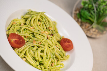 Green spinach spaghetti with cheese and tomato on wooden table