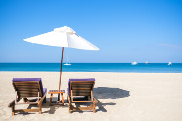 White beach umbrella on the beach against the blue sky and blue sea background on sunny day. Summer vacation and holiday concept. © Missleestocker