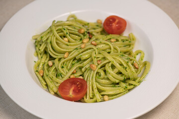 Green spinach spaghetti with cheese and tomato on wooden table