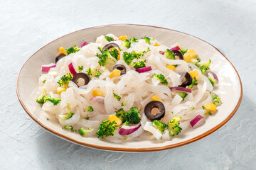 Konjac pasta, a plate of low-calorie fettuccine with broccoli, onions, and other vegetables, a healthy vegan dinner