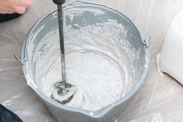 A male worker spreads the putty mixture and flattens the wall.
