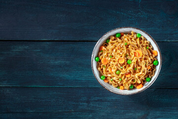 Noodles with green peas and carrots, shot from above with a place for text