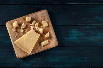 Crumbled Parmesan cheese, shot from the top on a dark blue wooden background with a place for text