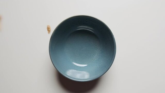 Top Down Pouring Cornflakes Cereal in Blue Bowl on White Table Top Slow Motion