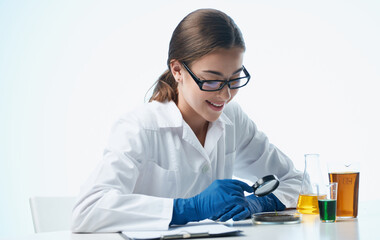 a nurse in a lab coat and blue gloves with a flask in her hand chemical element laboratory analyzes