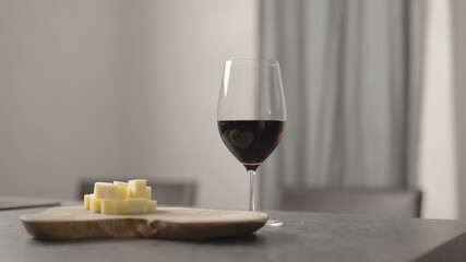 red wine into wineglass with hard cheese on background on wood table
