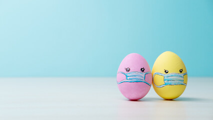 Coronavirus composition. Easter background. Lockdown quarantine. Pastel color painted egg couple in protective face mask cute pattern on light blue conceptual empty space poster.