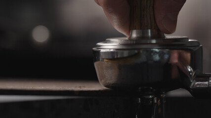 man tamping freshly ground coffee in portafilter
