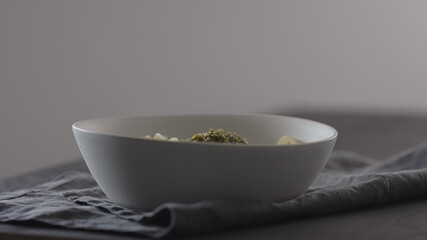 put pesto on fettuccine in white bowl on linen cloth