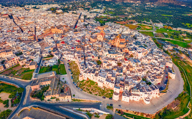 Aerial landscape photography. Colorful spring view from flying drone of Ostuni town, Italy, Europe. Stunning sunrise on Apulia. Traveling concept background. Amazing morning cityscape of Ostuni.