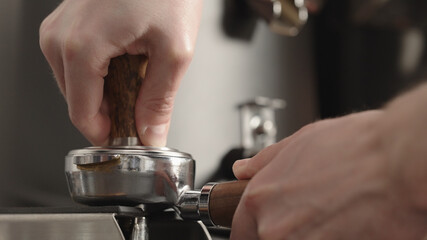 man tamping freshly ground coffee in portafilter