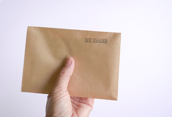 Woman holding a brown envelope with rubber stamp, by hand at the top.