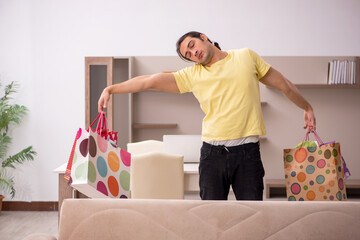 Young man with many bags in Christmas concept at home