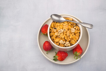 bowl of corn flakes cereals and spoon isolated on grey background.