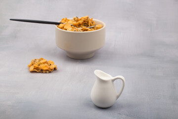 bowl of corn flakes cereals and spoon isolated on grey background.