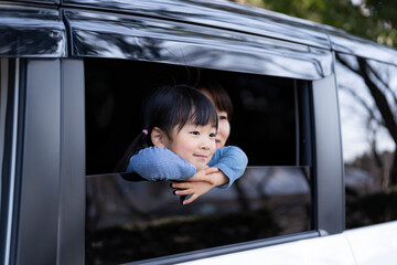 自動車の窓から外を眺める日本人親子