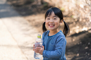 ペットボトルを持つ笑顔の日本人の女の子