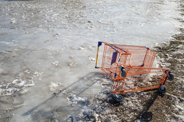 Broken shopping cart on outdoor icy ground.