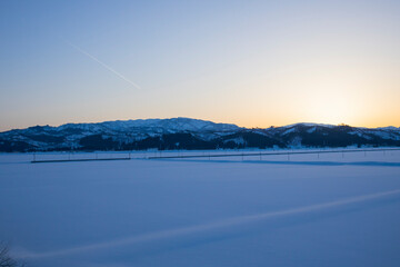 雪原の夕焼けと飛行機雲