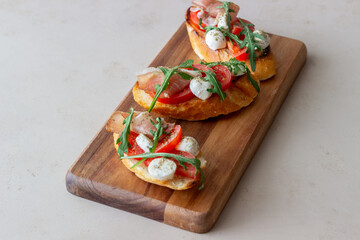 Bruschetta with ham, mozzarella, tomatoes and arugula. Wine appetizer. Snack.