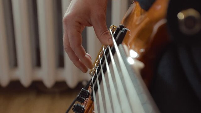 The musician rehearses at home on a six-string bass guitar. Close-up. Soft Focus