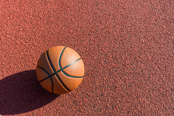 Orange ball for basketball lying on the sport outdoor court.Sport red court.Copy space.Top view.