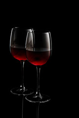 two glasses of red wine on a black background