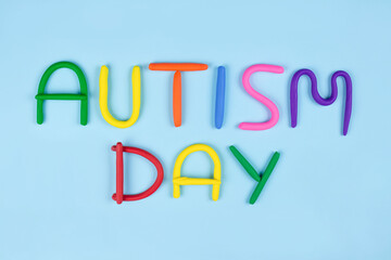 World Autism Awareness Day concept - multicolored letters made of play-doh or other sensory playfoam on blue background. Autism spectrum disorder and child mental health concept. Selective focus