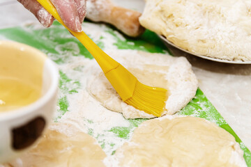 Cooking from dough. Grease the dough with a silicone brush oil. Making pies at home.