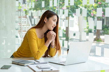 Portraits of beautiful smiling Asian women relax using laptop computer technology while sitting on their desks and using their creativity to work, work from home concept.