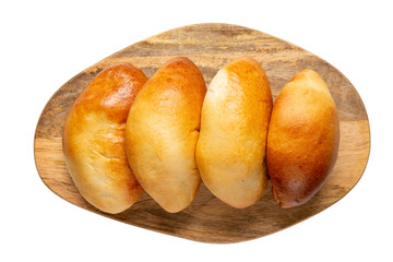 Four pies in row on wooden cutting board isolated on white. Oven baked patties with filling. Traditional Russian pasties pirozhki. Delicious pastries. Top view.