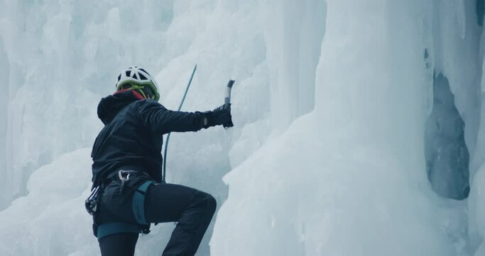 Climber man ice climbing frozen waterfall winter extreme sport scene