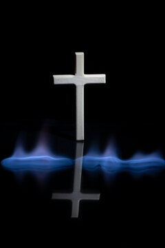 Cross or crucifix with reflection in the darkness. Burning fire flames.