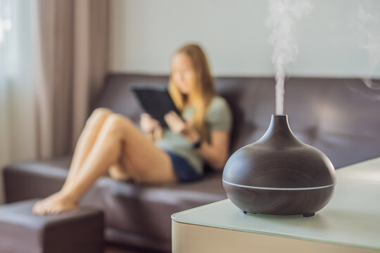 Aromatherapy Concept. Wooden Electric Ultrasonic Essential Oil Aroma Diffuser and Humidifier. Ultrasonic aroma diffuser for home. Woman resting at home