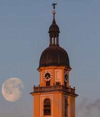 Petrini Kirche Kitzingen im Licht der aufgehenden Sonne im Hintergrund der sinkende Mond 