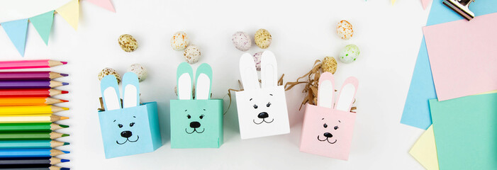 Crafts with children for Easter from colored paper. Boxes bunnies for sweets in the form of eggs. Flat lay.