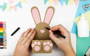 The concept of crafts with children for the Easter holiday. Step-by-step instructions for making craft paper bunny boxes. Step 5- draw a bunny face.